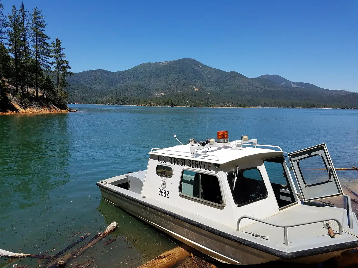 A boat on Shasta Lake along a forested shoreline